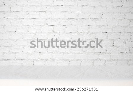 Empty table covered with wrinkled tablecloth over white brick wall background, for product display montage