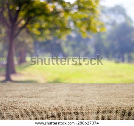 Empty table and sack tablecloth over blur tree with bokeh background, for product display montage