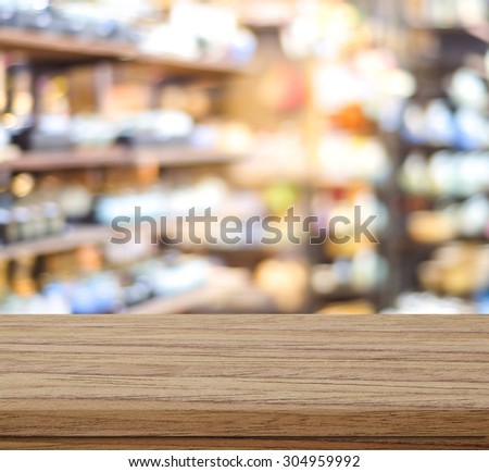 Empty table over blur product shelf in supermarket with bokeh background, product display montage