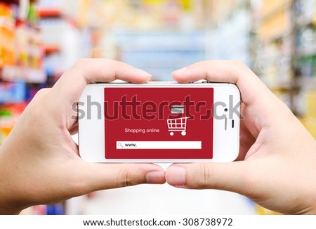 On line shopping on smart phone screen over blur supermarket background, business, E-commerce, technology and digital marketing background