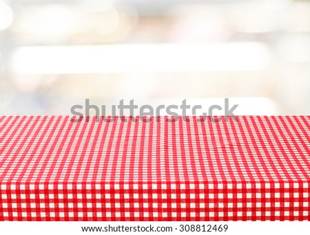 Empty table with red check tablecloth over blur festive bokeh background, product display