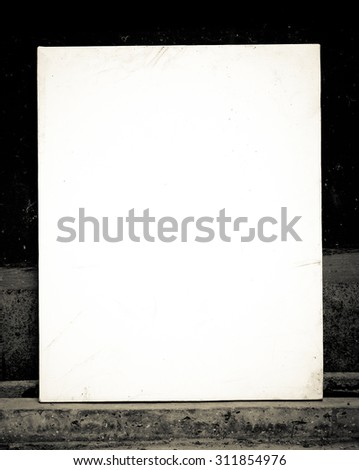 Blank canvas frame over gunge wall background, vintage filtered