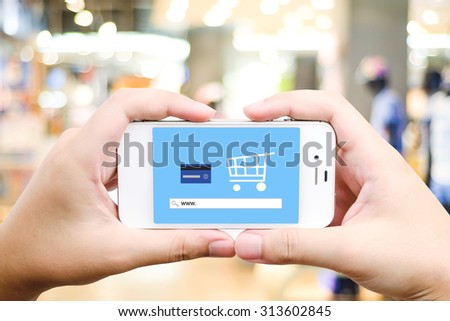 Hand holding smart phone with www. on search bar over blur store background on screen, on line shopping ,business, E-commerce, technology and digital marketing background