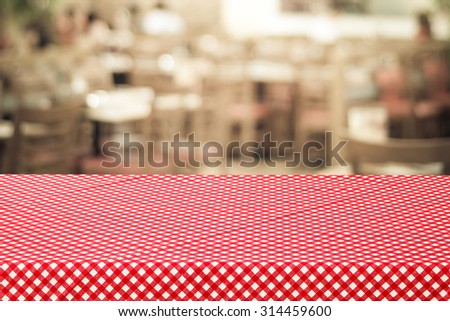 Empty table covered with red check tablecloth over blurred restaurant with bokeh light background, product, food display template