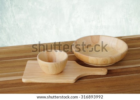 Empty wooden tray, bowl and plate on table over cement wall background, template, food display montage
