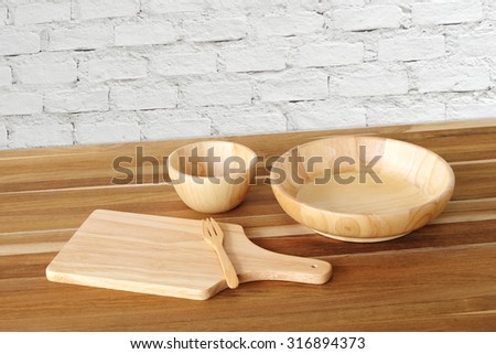 Empty wooden tray, bowl, plate and fork on table over white brick wall background, template, food display montage
