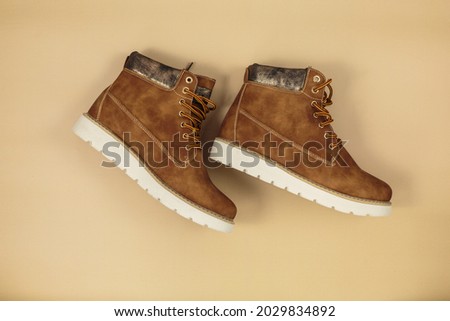 Orange leather boots on beige background. Pair of elegant modern brown footwear on the table. Trendy autumn accessories. Cozy outfit Foto stock © 