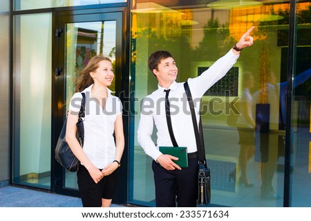 Two Caucasian business people pointing and looking at something.