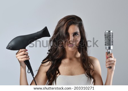 Beautiful young woman with the hair dryer and brush