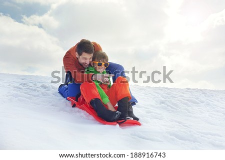 father and son having fun in the snow, sliding
