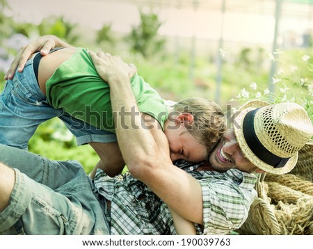 Young boy playing with his father in a green house