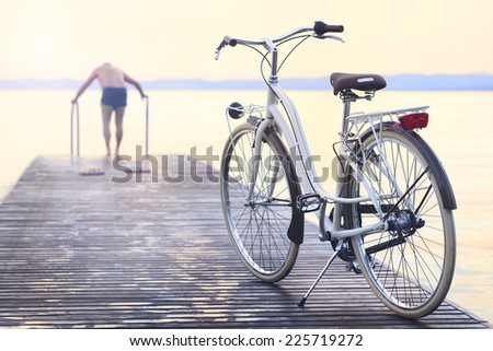 man parks bike on boardwalk before jumping into the water