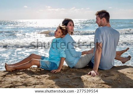 Happy Small Family Sitting at the Beach on a Sunny Climate