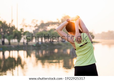 Young beautiful Asian woman in sports outfits doing stretching before workout outdoor in the park in the morning to get a healthy lifestyle. Healthy young woman warming up outdoors.