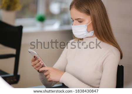 Female customer in beauty salon sitting in medical mask and use phone. Beautiful young blond hair woman wiating for brow master Zdjęcia stock © 