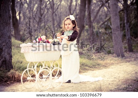 Cute girl in vintage clothes with flowers in pram