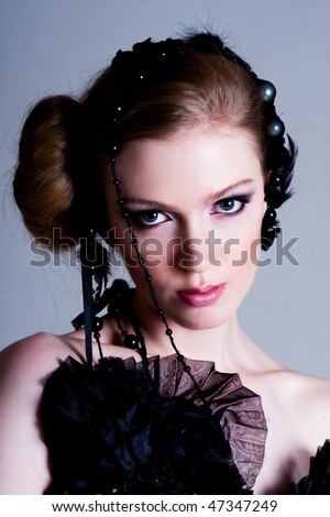 Attractive young woman wearing black feather and pearl hair dressings. Vertical shot.