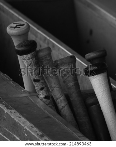 Black and white image of baseball bats in a dugout