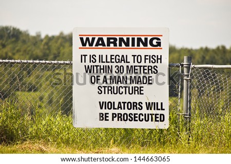 A warning sign that it\'s illegal to fish close to a man made structure