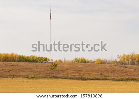 A communications tower by farmland and fall colored trees