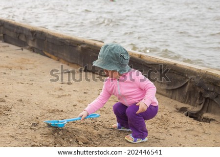 Little girl in floppy hat playing on the beach