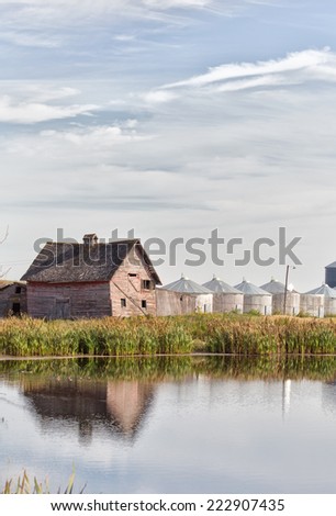 Shed and old grain bins reflected in pond