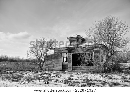 Abandoned one room school house on the prairies in black and white