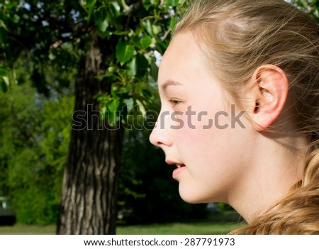 Side view of the face of a teenage girl with long hair pulled back and hanging over her shoulder