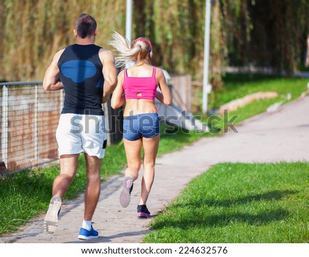fitness, sport, friendship and lifestyle concept - smiling couple  running outdoors