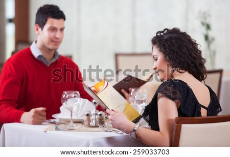 Cheerful couple with menu in a beautiful restaurant making order