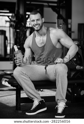 Young adult man drinking protein shake in modern gym