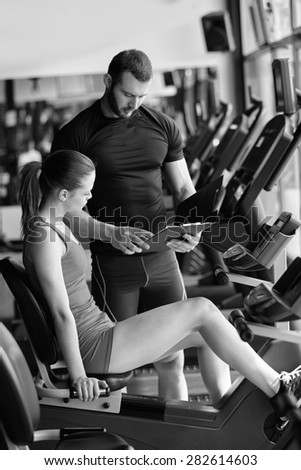 gym woman personal trainer man with weight training equipment in modern gym