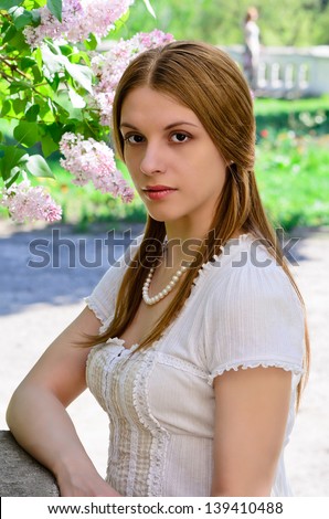 Beautiful girl in a spring garden with a pearl necklace