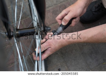 man pump up the bike wheel outdoor on the city street