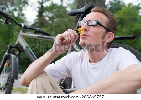 Summer rest. Man sniffing the yellow flower.