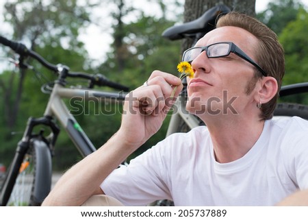 man with funny face sniffing the flower