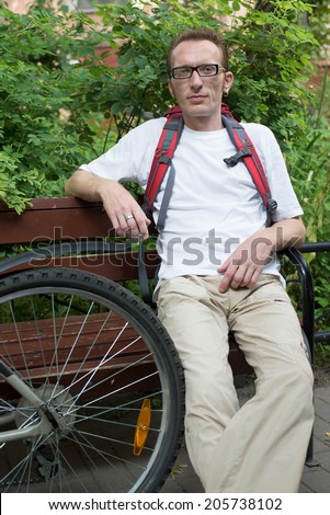 Man with  bicycle rest on the bench