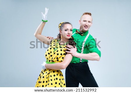 Portrait lovely funny dancer couple dressed in boogie-woogie rock\'n\'roll pin up style posing together in studio. Woman in yellow polka dots dress and man in green shirt.