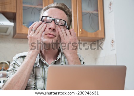 the young man rubs tired eyes after a full day of work at the computer