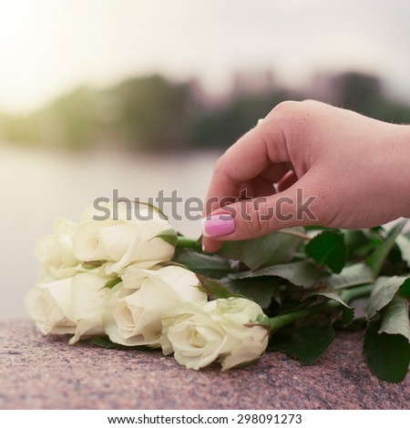 Bouquet of white roses and hand on the stone parapet in the evening