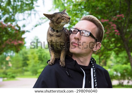 close up cat and a man portrait outdoor on owner\'s shoulder