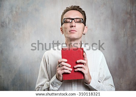 man praying with close eyes rise his face up and hug a bible in his hands.