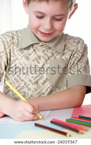 6 year old boy draws pencils sitting for a table