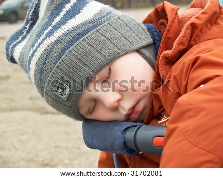 The little boy sleeps in the street in the spring