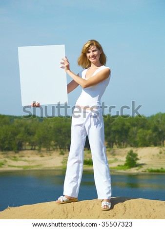 The beautiful girl in white clothes holds the board on the nature