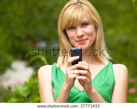 The girl in a green dress talks by a mobile phone
