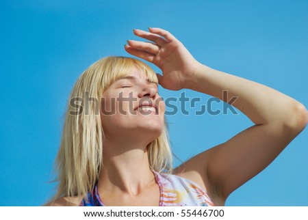 The young woman poses with the lifted hands on a background of the dark blue sky