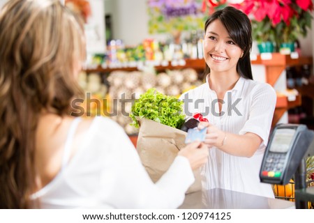 Shopping woman at the checkout paying by card