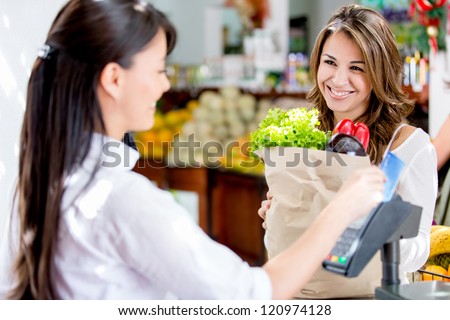 Woman at the local market's checkout paying by debit card