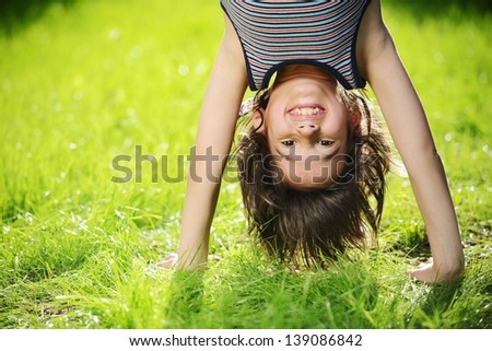 Portraits of happy kids playing upside down outdoors in summer park walking on hands 商業照片 © 